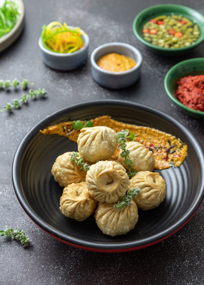 Crispy fried momos in a black bowl with chutney